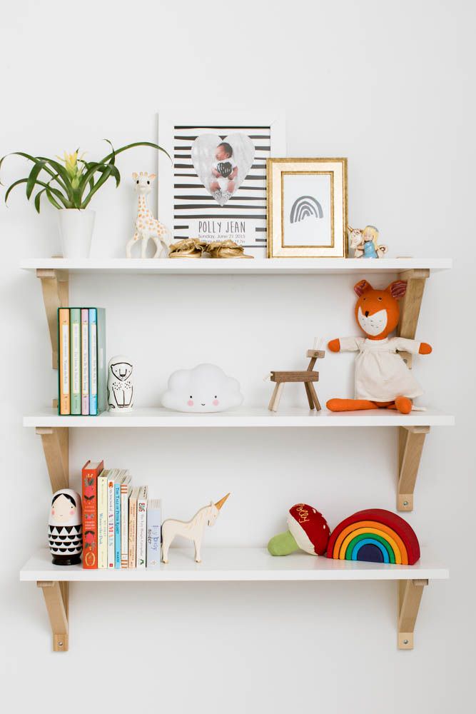 اتاق نوزادی که در آن کتاب، اسباب بازی و دکوری ها روی قفسه های دیواری چیده شده است